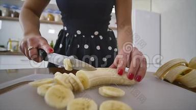 女人在家庭<strong>厨房</strong>的木制<strong>厨房</strong>板上切香蕉。 在家做饭。 <strong>厨房</strong>里的家庭气氛